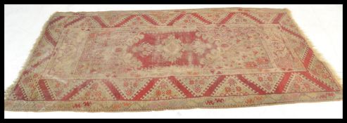 A early 20th Century handwoven Islamic - Persian woollen floor carpet rug having a red ground