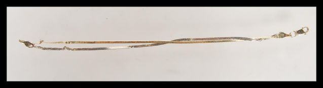 A stamped 14ct gold two tone flat link bracelet having a yellow gold and a white gold chain on a