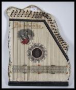 An early 20th Century Pianochordia  instrument having a white backboard being printed with foliate