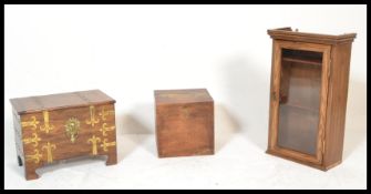 A 20th Century elm glazed fronted hanging cabinet together with a brass bound chest having a