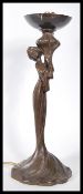 A 20th century Art Nouveau bronze effect table lamp in the form of a maiden holding a flower stem.