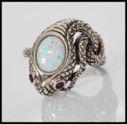 A silver ring in the form of a snake having ruby eyes and opalite cabochon to head, the snake body
