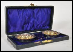 A pair of silver hallmarked table salts having embossed scrolled decoration with matching spoons set