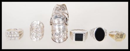 A selection of silver rings to include a a gold plated signet ring, a pierced decoration ring, a