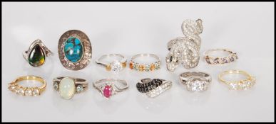 A group of twelve stamped 925 silver rings to include a serpent ring set with white stones, a