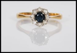 A stamped 18ct gold ring set with a round cut sapphire having a halo of eight diamonds. Weight 3.0g.