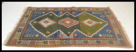 A vintage 20th Century oriental rug having green and blue ground, with geometric pattern border