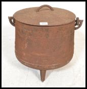 A large vintage 20th Century cast iron pot bellied cauldron with lid raised on a tripod base,