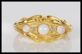 A silver gilt Victorian style ring set with three opals and two small white stones on a scroll
