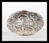 An early 20th Century silver hallmarked snuff / pill box of bulbous form having repousse floral