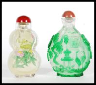Two 20th century Chinese glass snuff bottles both with stoppers, the first having had painted