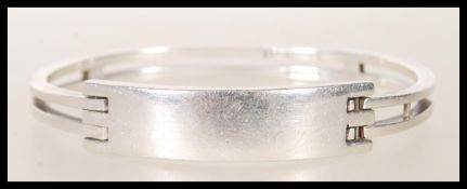 A stamped 925 silver bangle bracelet having square bars culminating in a square geometric clasp.