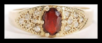 A 9ct gold diamond and garnet hallmarked London ring. Oval garnet adorned with diamond chip accented