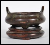 A Chinese bronze censer ding prayer bowl raised on three conical feet and twin hoop handles.