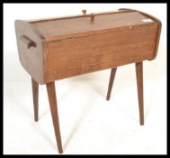 A vintage retro wooden sewing box having twin doors with knob handles to the top, raised on tapering