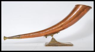 A vintage 20th Century copper hunting horn, having brass mouthpiece and collar. Raised on a