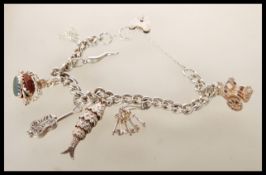 A silver hallmarked heart lock charm bracelet having seven charms including an articulated fish, a
