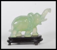 A 20th Century Chinese carved jadeite elephant on all four legs raised on a ebonised wooden base.