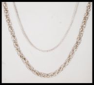 Two silver necklace chains to include a snake chain with an S clasp and a rope link necklace. Both