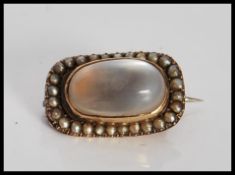A 19th Century Georgian rose gold brooch being set with a central moonstone cabochon having a border