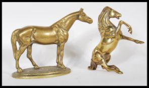 Two 20th Century brass horses, one horse stood on an oval cobblestone effect base having detailing