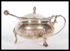 A silver hallmarked lidded mustard pot of bulbous form raised on the cabriole feet having a hinged