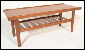 A retro 20th century teak wood coffee table raised on shaped supports united by slated under tier