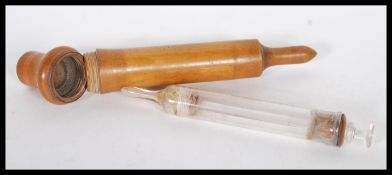 A early 20th Century treen / olive wood cased glass syringe, having screw top to the case.
