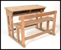 An early 20th century country pine childs 2 seater school desk. The bench seat united by lower rails