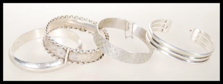 A selection of four silver bangle bracelets to include a hallmarked bangle with graved decoration
