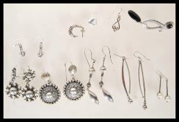A selection of silver earrings to include a pair of drop earrings set with pearls, a pair of knot