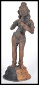 An Indian cast metal figure depicting the Hindu deity Krishna depicted playing a flute on a round