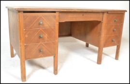 A mid century Air Ministry style oak twin pedestal desk. Raised on shaped legs having open