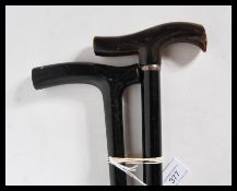 A pair of 20th Century crook handle walking sticks/ canes, having tapering ebony shafts, one