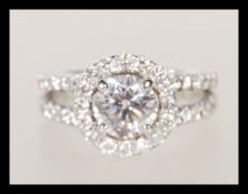 An 18ct white gold diamond ring having a central brilliant cut diamond with a halo of smaller stones
