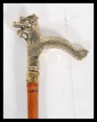 A bamboo walking stick/ cane, having a brass handle in the form of a Chinese dragon and brass