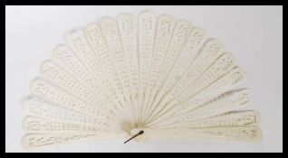 An early 20th Century ivory fan having 20 carved panels with pierced decoration having a brass pin.