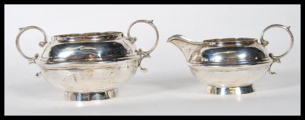 A silver hallmarked William Neale creamer jug having a scrolled handle raised on a circular base