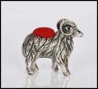 A sterling silver novelty pincushion in the form of the ram, having red baize pin cushion to top.