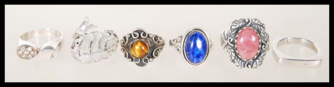 A selection of silver rings to include a ring set with a blue cabochon, a ring set with tigers