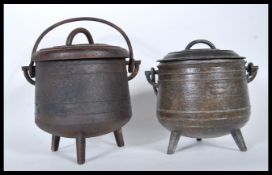 A pair of vintage 20th Century cast iron pot bellied cauldrons with lids, the pots used for the