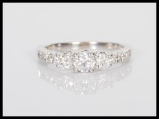 A stamped 14ct white gold dress ring prong set with a central brilliant cut diamond flanked by two