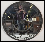 A large contemporary ebonised iron framed skeleton wall clock, mirrored backed and iron roman
