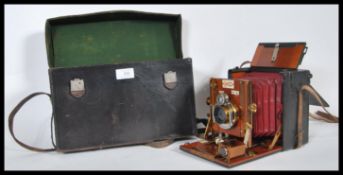 A Sanderson Patent quarter plate hand camera having mahogany casing brass fittings and red leather