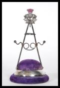 A silver hallmarked Britton, Gould & Co hat pin stand having a purple velvet cushion base with a