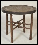 A 20th Century Indian brass topped Binares occasional table having engraved patterned decoration and