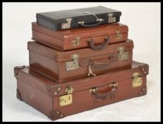 A stack of vintage leather suitcases and cases to include, two brown leather suitcase having