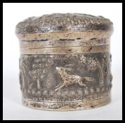 A 20th Century Anglo Indian silver white metal lidded jar decorated with hunting scenes in