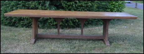 An early 20th Century Arts and Crafts twelve foot solid oak refectory dining table, being raised