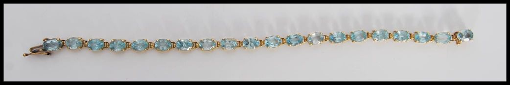 A stamped 14k / 14ct gold bracelet being set with oval cut aquamarine stones, having a tongue and